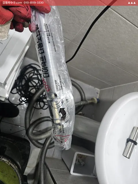 교체용 세면대 배수 부속을 든 손